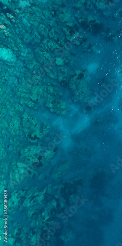 Zenithal view of the clean and crystalline water of the sea of Sardinia, Italy. There are rocks and reefs under the waves. The water surface is calm. Ideal for texture and pattern.