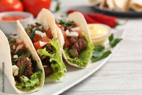 Delicious tacos with meat and vegetables on wooden table, closeup