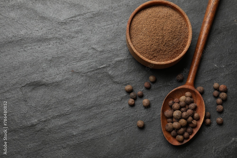 Ground and whole allspice berries (Jamaica pepper) on black table, top view. Space for text Ground and whole allspice berries (Jamaica pepper) on black table, top view. Space for text