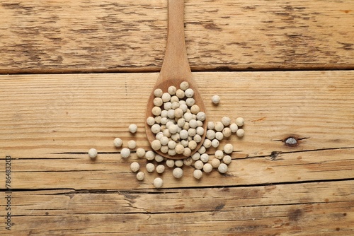 Aromatic spice. White pepper in spoon on wooden table, top view