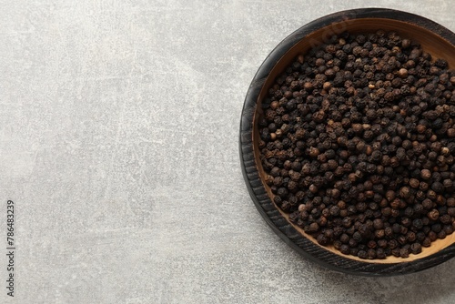 Aromatic spice. Black pepper in bowl on light grey table, top view. Space for text