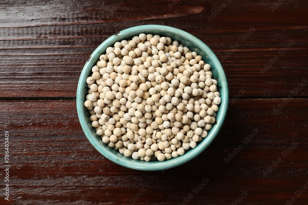 Aromatic spice. White pepper in bowl on wooden table, top view Aromatic spice. White pepper in bowl on wooden table, top view
