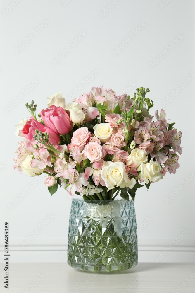 Obraz premium Beautiful bouquet of fresh flowers in vase on table near white wall