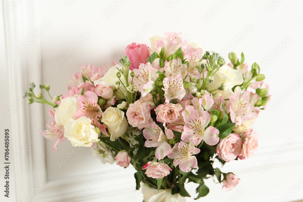 Beautiful bouquet of fresh flowers near white wall