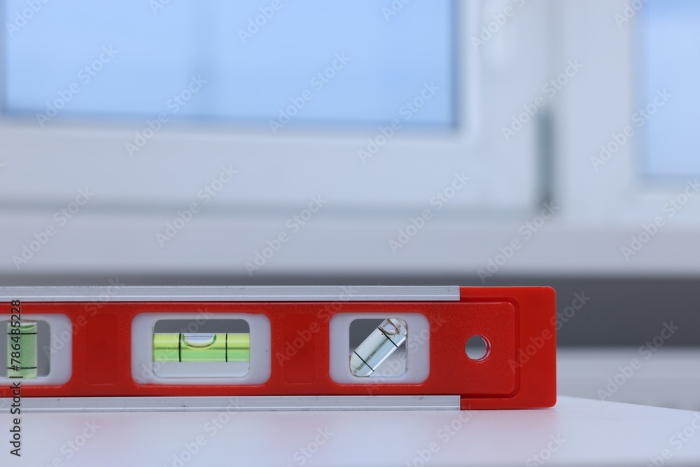 Red building level on white windowsill indoors, closeup Red building level on white windowsill indoors, closeup