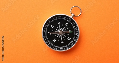 One compass on orange background, top view