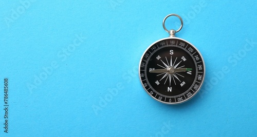 One compass on light blue background, top view. Space for text
