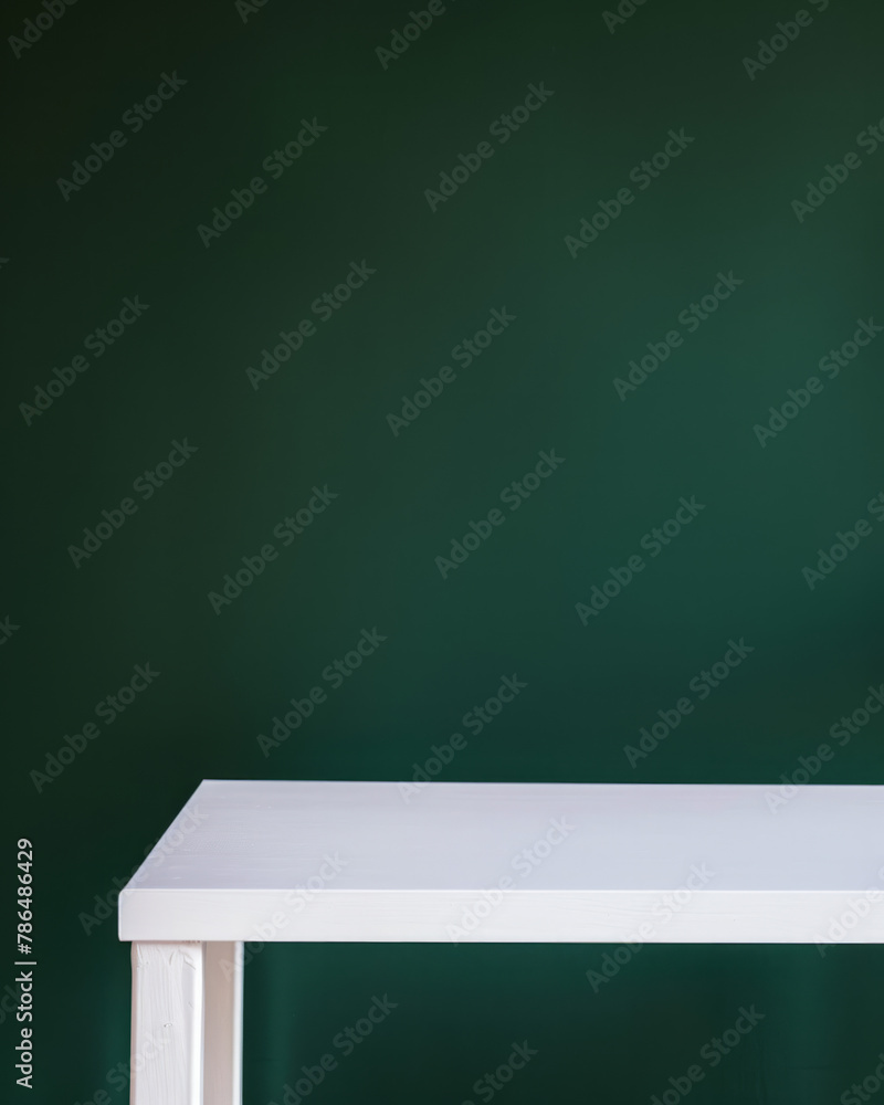 Closeup photo of clean white table with dark green room in background. Closeup photo of clean white table with dark green room in background.