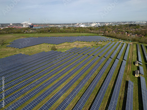 Low altitude aerial view of Solar Farm in Marchwood, UK. Solar panel lines with view towards Power Station and Southampton container terminal.