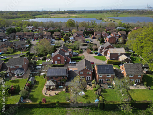 Aerial view of solar panels on the roofs of residential houses and solar farm in Marchwood, Southampton, UK. Closeup view of Marchwood residential area with houses and green gardens.