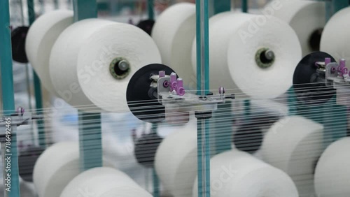 working warping machine and thread spools close-up, threads quickly unwinding