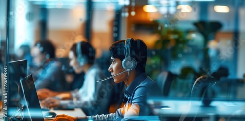 Photo of busy call center with headsets. Business people working on laptops with a blurry background.