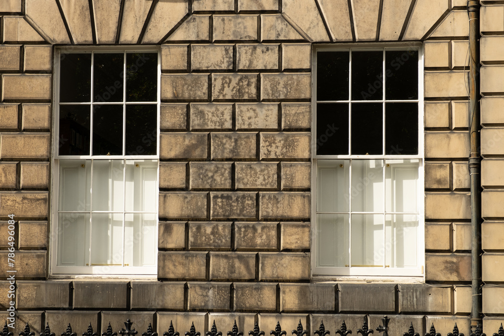Obraz premium Two identical traditional white sash windows in stone wall of house in Edinburgh, Scotland