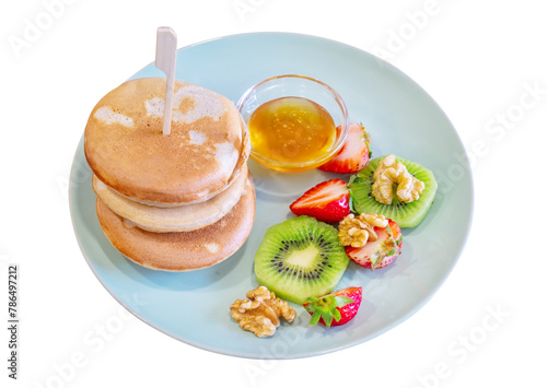 Delicious golden pancakes cooked on a dry griddle and served for breakfast with honey and kiwi pecans and strawberries. 