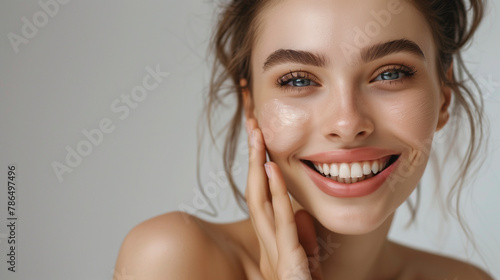 High-resolution cropped photograph showcasing skincare and cosmetics concept, featuring ample space for text. A woman with a stunning visage gently caresses her radiant, healthy facial skin in the por