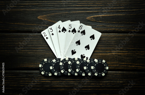 Chips and playing cards with straight flush winning combination on a black vintage table. Concept of winning in a poker club or casino photo