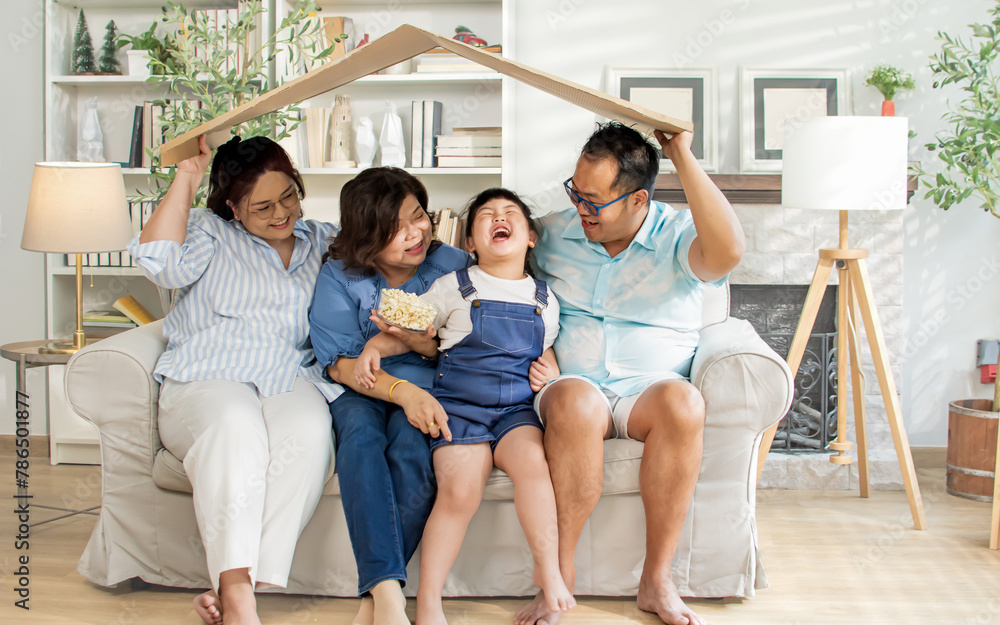 Asian cheerful family, four members wearing casual clothes, holding paper roof, present home loan, real estate, interior, smiling with happiness, warmth, sitting on sofa in cozy living room at home. Asian cheerful family, four members wearing casual clothes, holding paper roof, present home loan, real estate, interior, smiling with happiness, warmth, sitting on sofa in cozy living room at home.
