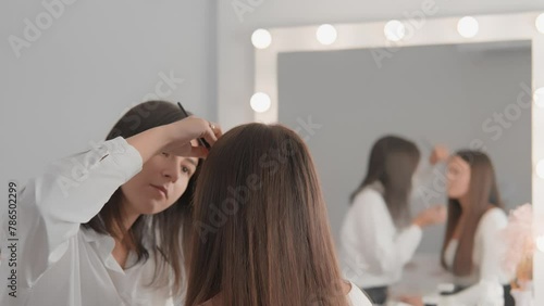 In cosmetology room, girl receives eyebrow lamination procedure to give them volume expressiveness. Artist uses microblading technology to create perfect eyebrows for client, giving them natural look. photo