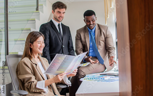 Three diverse multiracial businesspeople wearing formal clothes, talking, seriously discussing idea about green energy sustainable business, sitting in modern indoor workplace or office.