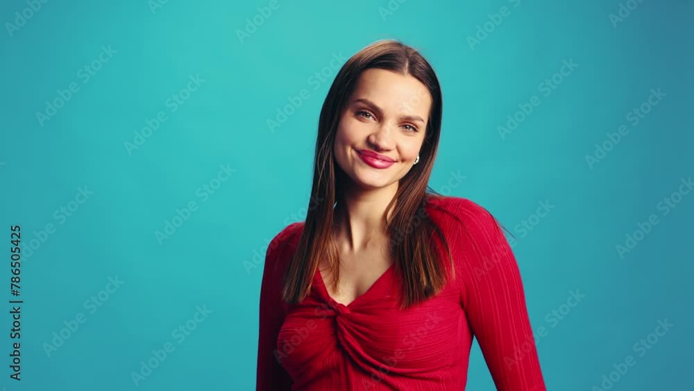 Happy young beautiful woman in red blouse posing with happiness, smiling, laughing against blue studio background. Concept of human emotions, facial expression, lifestyle Happy young beautiful woman in red blouse posing with happiness, smiling, laughing against blue studio background. Concept of human emotions, facial expression, lifestyle