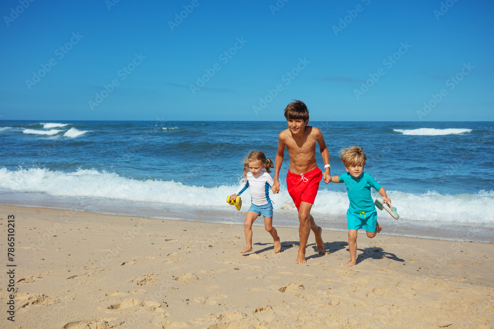 Joyful beach chase of friends under sun with waves on background