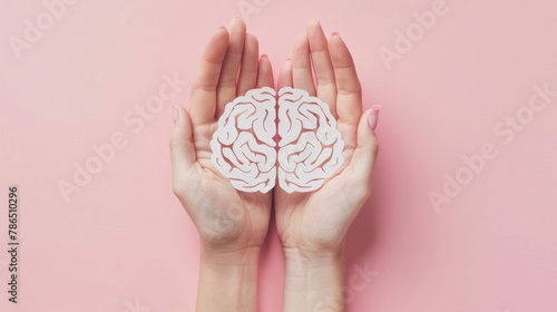 Hands holding brain paper cutout on pink background World mental health celebration