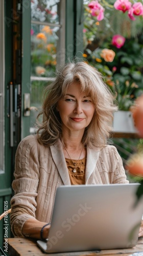 Portrait of modern middle-aged woman with pleasant appearance working with laptop in home garden, home office, online work