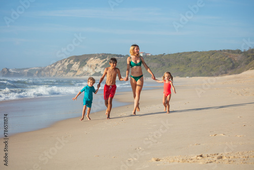 Family enjoy leisure run along sandy shoreline with waves crash