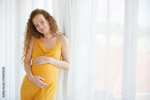 pregnant woman smiling and relaxing in the bedroom