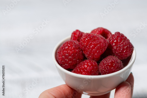 fresh raspberries in a white bowl in hand