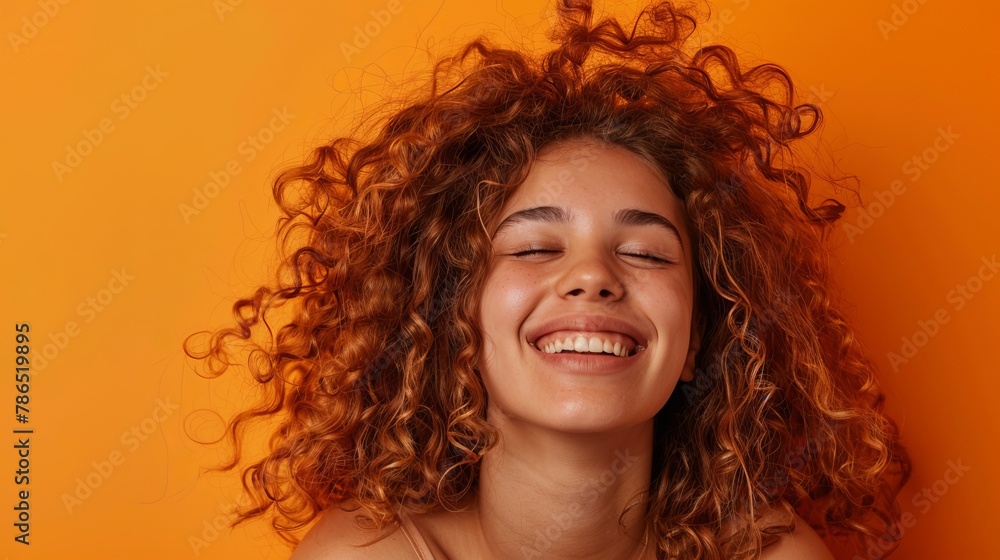 Happy woman with curly hair on orange background, smiling Happy woman with curly hair on orange background, smiling