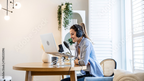 Woman wearing headphones sitting at a desk speaking into microphone and recording a podcast 