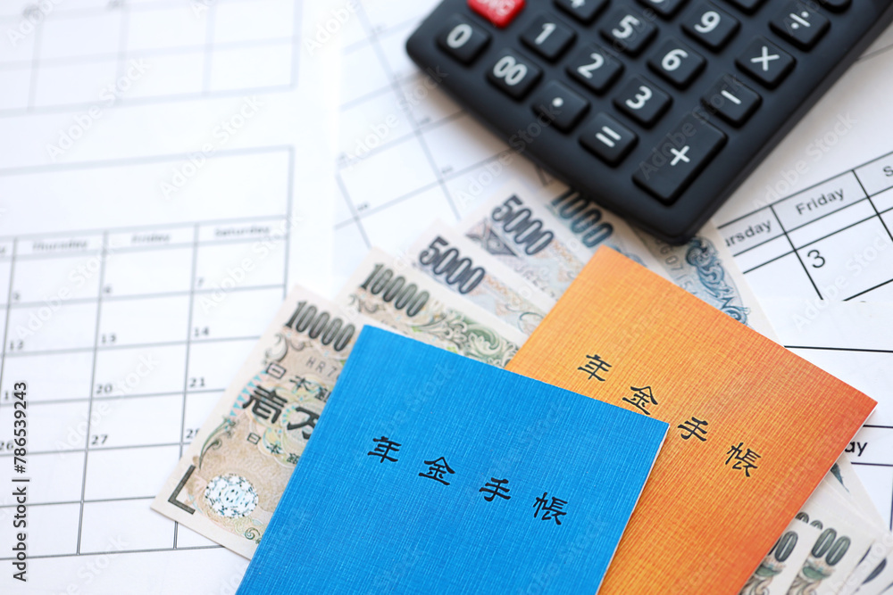 Japanese pension insurance booklets on table with yen money bills and calculator on table close up Japanese pension insurance booklets on table with yen money bills and calculator on table close up