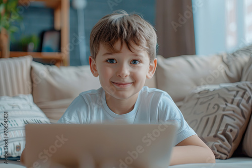 Portrait of happy boy playing with computer. Attractive kid with a laptop at home photo