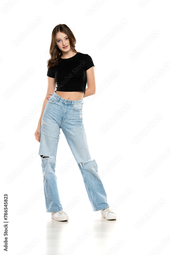 Young female model wearing ripped jeans and black shirt posing on a white background. Front view Young female model wearing ripped jeans and black shirt posing on a white background. Front view