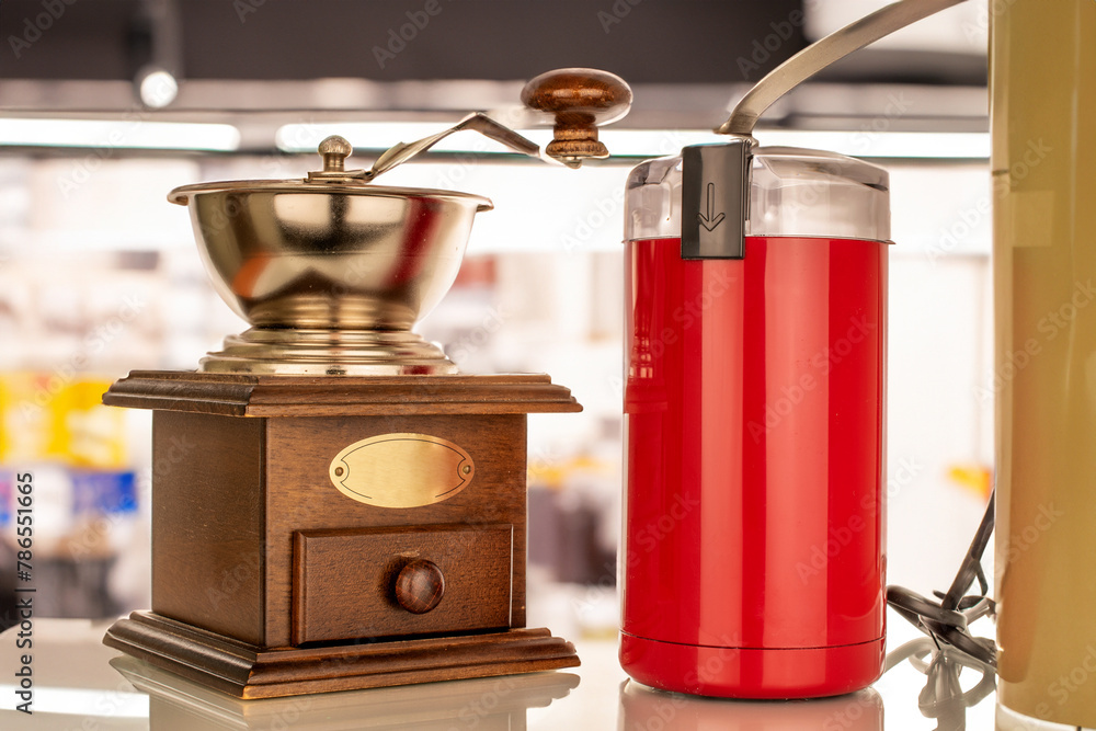 One electric coffee grinder with a manual coffee grinder on the table in the kitchen, macro. One electric coffee grinder with a manual coffee grinder on the table in the kitchen, macro.