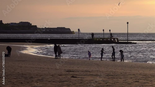 family playing on the beach at sunset