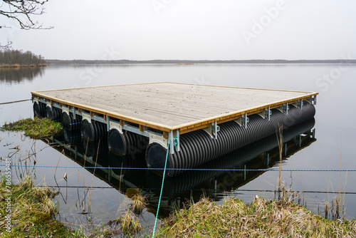 A new empty wooden platform on pontoons in the lake for the creation of a holiday house on the water