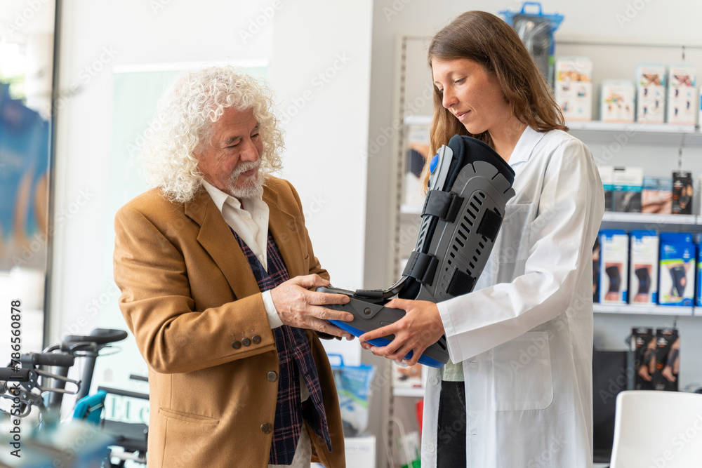Naklejka premium Senior man tries on an orthopedic boot at the pharmacy