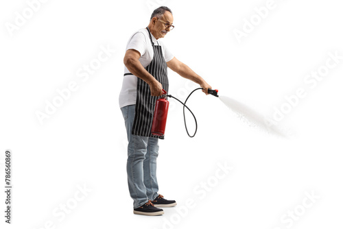 Mature man with a kitchen apron using a fire extinguisher