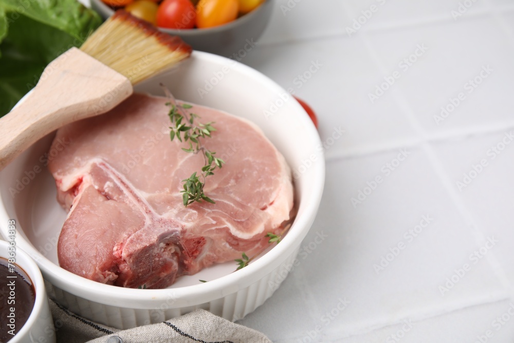 Raw meat, thyme and brush with marinade on white tiled table, closeup. Space for text Raw meat, thyme and brush with marinade on white tiled table, closeup. Space for text