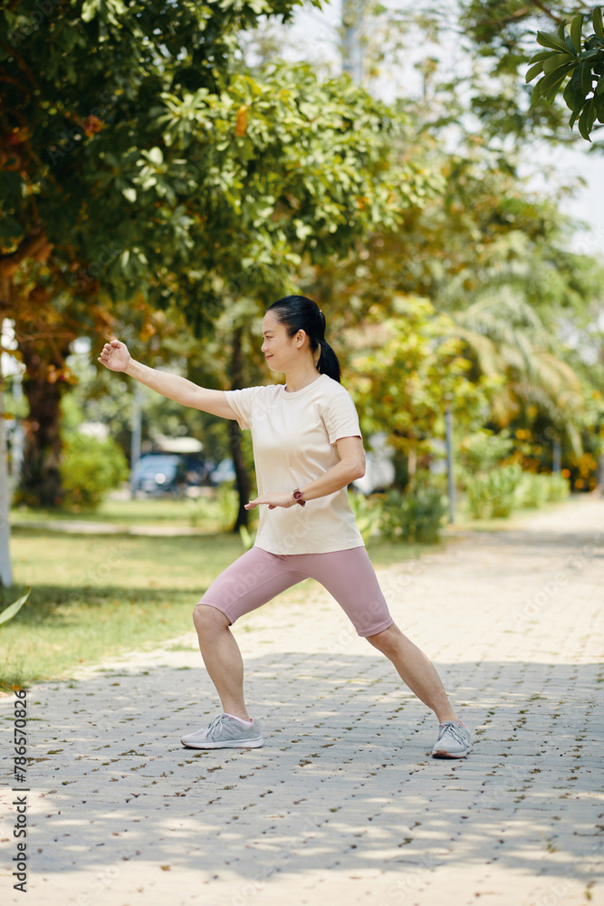 Fit mature woman exercising in park on sunny morning Fit mature woman exercising in park on sunny morning