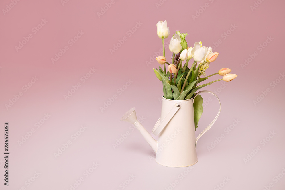 Bouquet of fresh pink tulips in teapots on a pink background. View with copy space. Spring holiday concept.