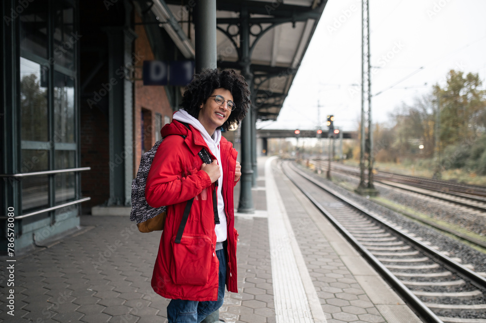 Guy in red jacket and with backpack waiting for the train at the platform