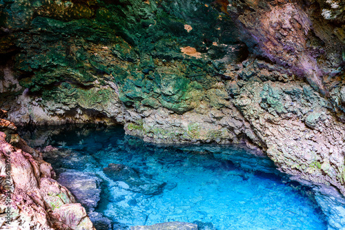 Stalactites and stalagmites in a Kuza cave at Zanzibar, Tanzania. Natural pool with crystal clear water photo