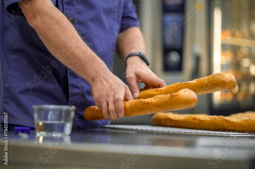 Unrecognizable man baker baking French baguette bread