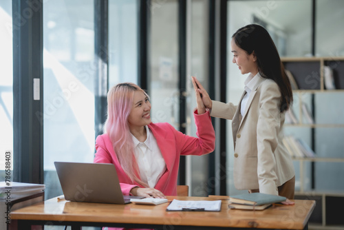 Φωτογραφία Two businesswomen celebrating their success with a high five in the office