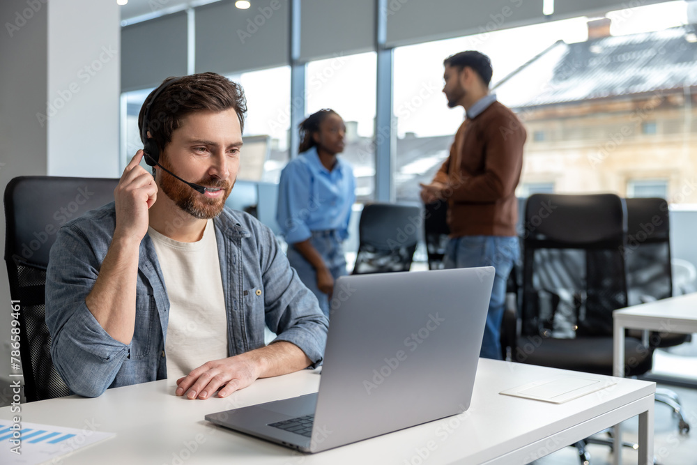 Naklejka premium Smiling man working in call center on phone with headset