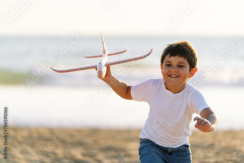 Smiling child proudly displaying a toy plane on the seashore photo