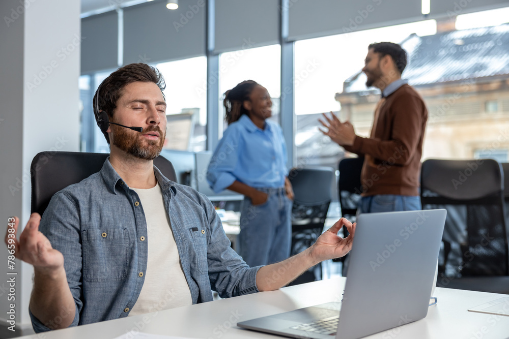 Naklejka premium Call center worker with headset meditating at his workplace